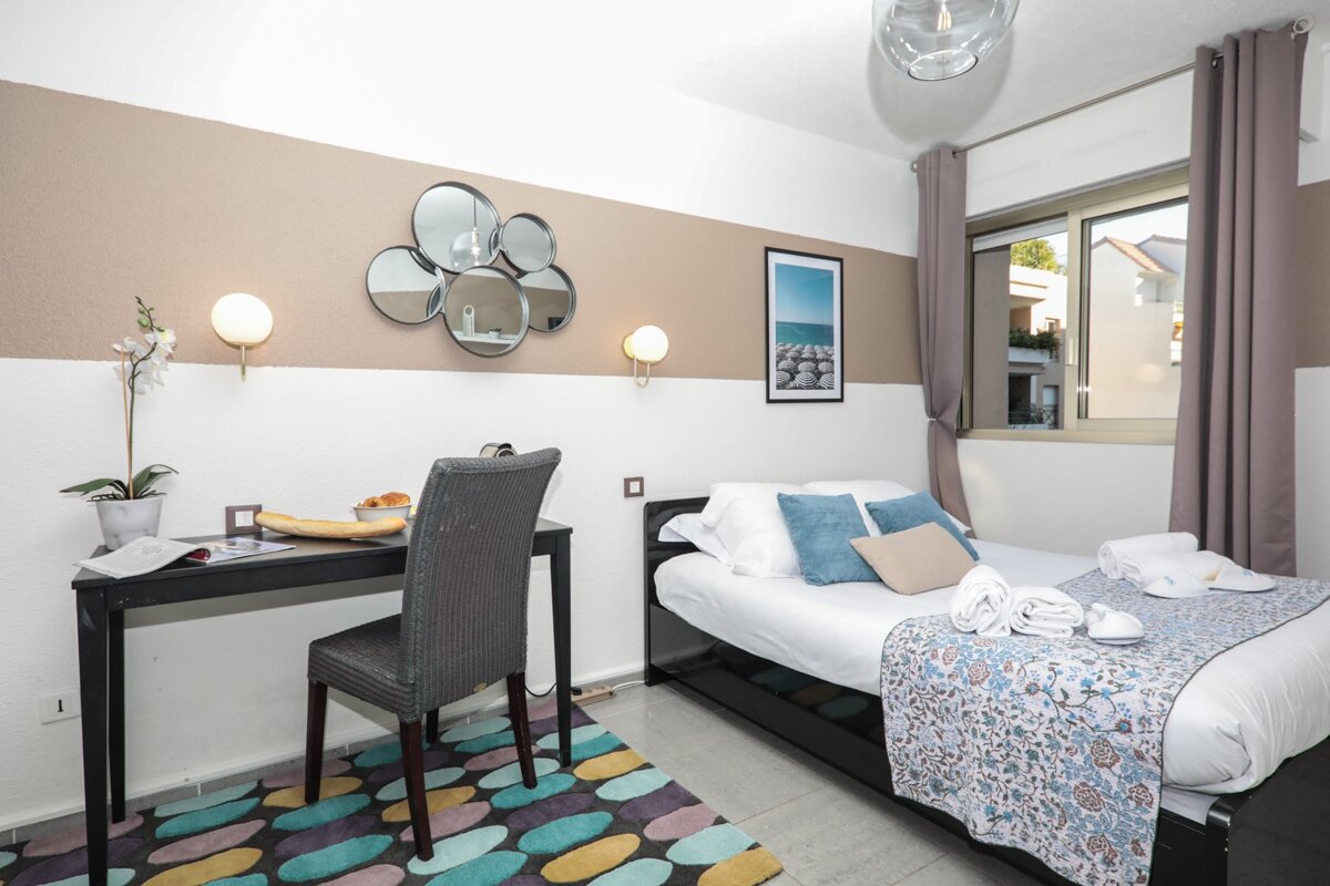 A bedroom with a bed a desk and a picture on the wall