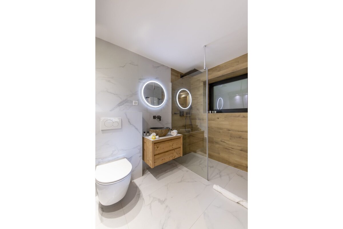 A bathroom with a toilet a sink and two mirrors