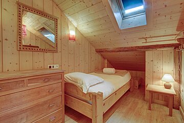 A bedroom with a single bed and a mirror