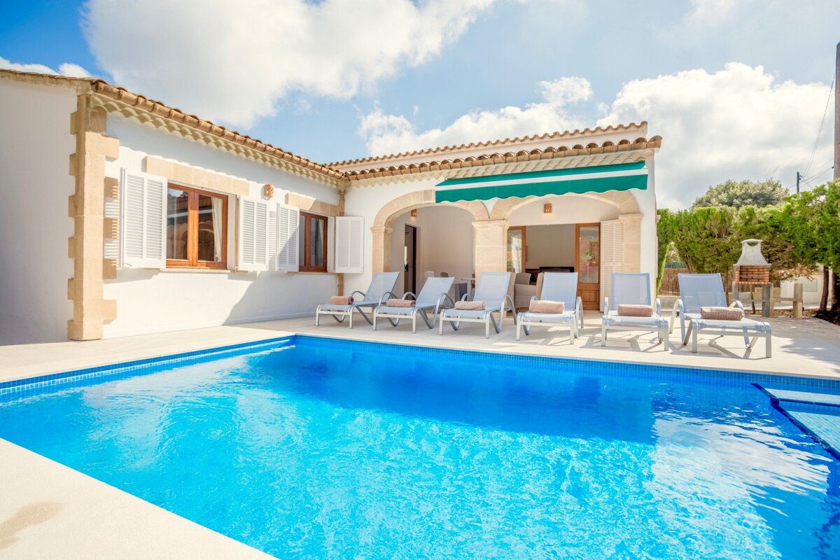 A white house with a large swimming pool in front of it