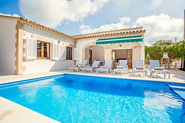 A white house with a large swimming pool in front of it