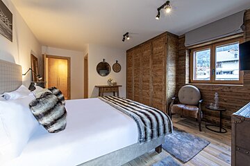 A bedroom with a large bed and a chair
