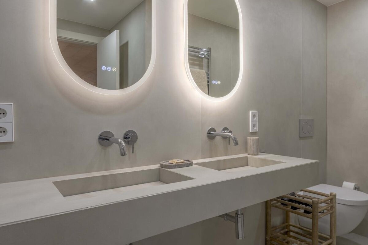 A bathroom with two sinks and two oval mirrors