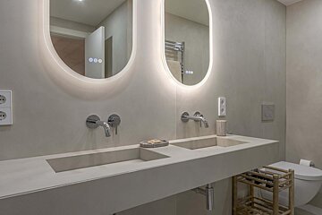 A bathroom with two sinks and two oval mirrors