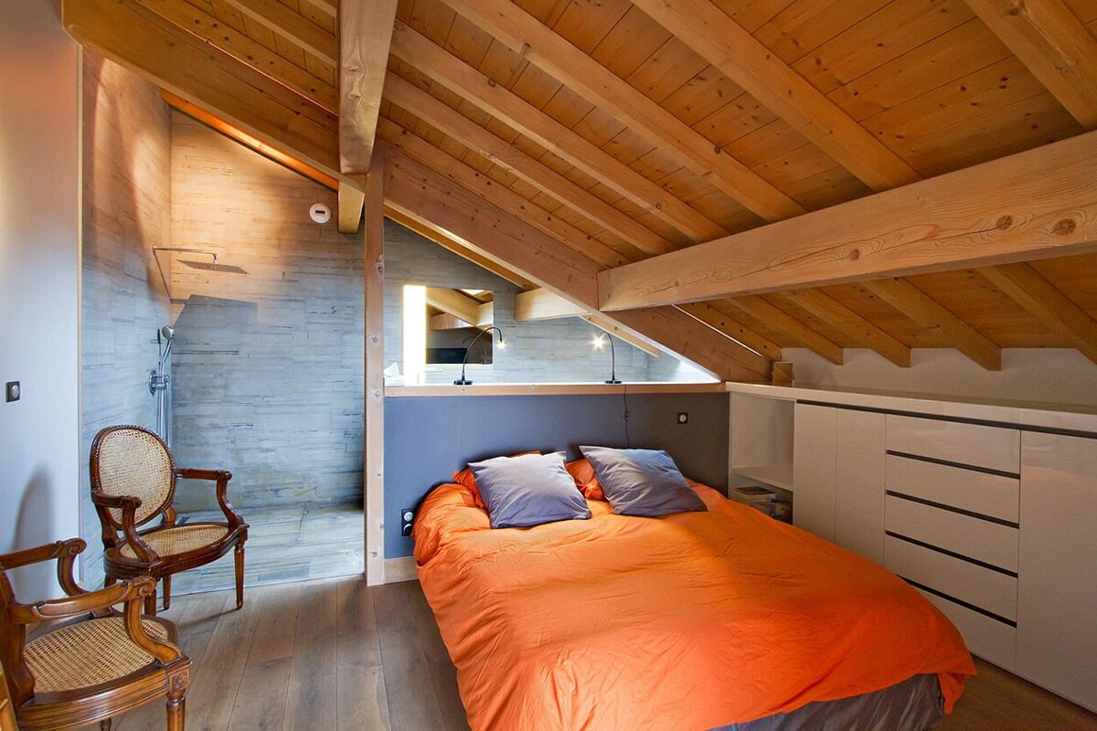 A bedroom with a wooden ceiling and an orange bed
