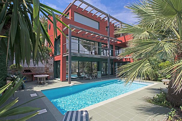 A large red house with a swimming pool in front of it