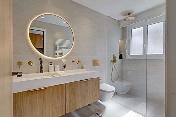 A bathroom with a round mirror and a toilet