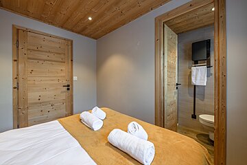 A bedroom with a wooden door leading to a bathroom