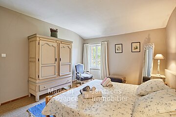 A bedroom with a bed and a wardrobe made in provence by janssens immobilier