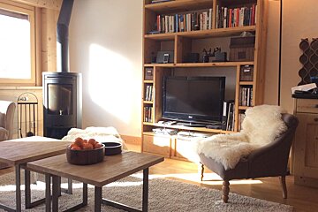 A living room with a lg tv and a bookshelf with books on it