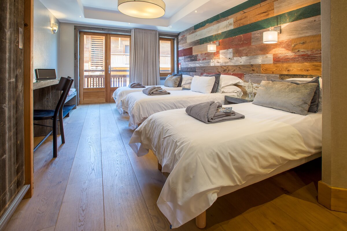 A hotel room with three beds and a wooden wall