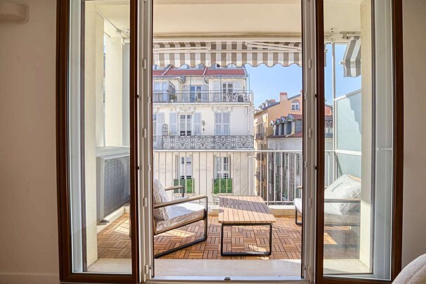 A balcony with a striped awning and a table and chairs