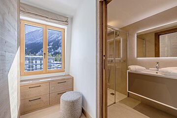 A bathroom with a shower and a window with mountains in the background