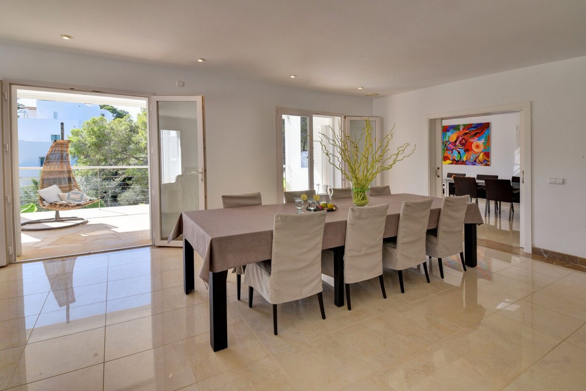 A dining room with a table and chairs and a painting on the wall