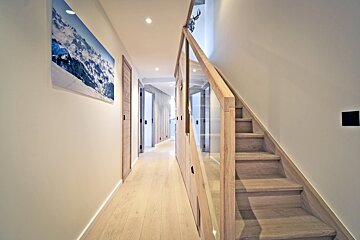 A hallway with stairs and a picture of a mountain on the wall