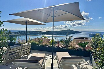 Two umbrellas are sitting on a balcony overlooking the ocean