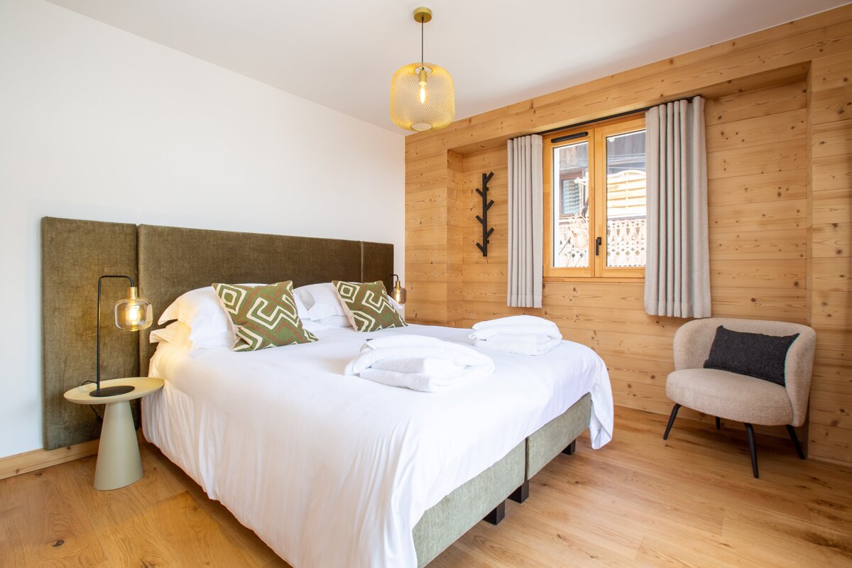 A bedroom with a large bed and a chair