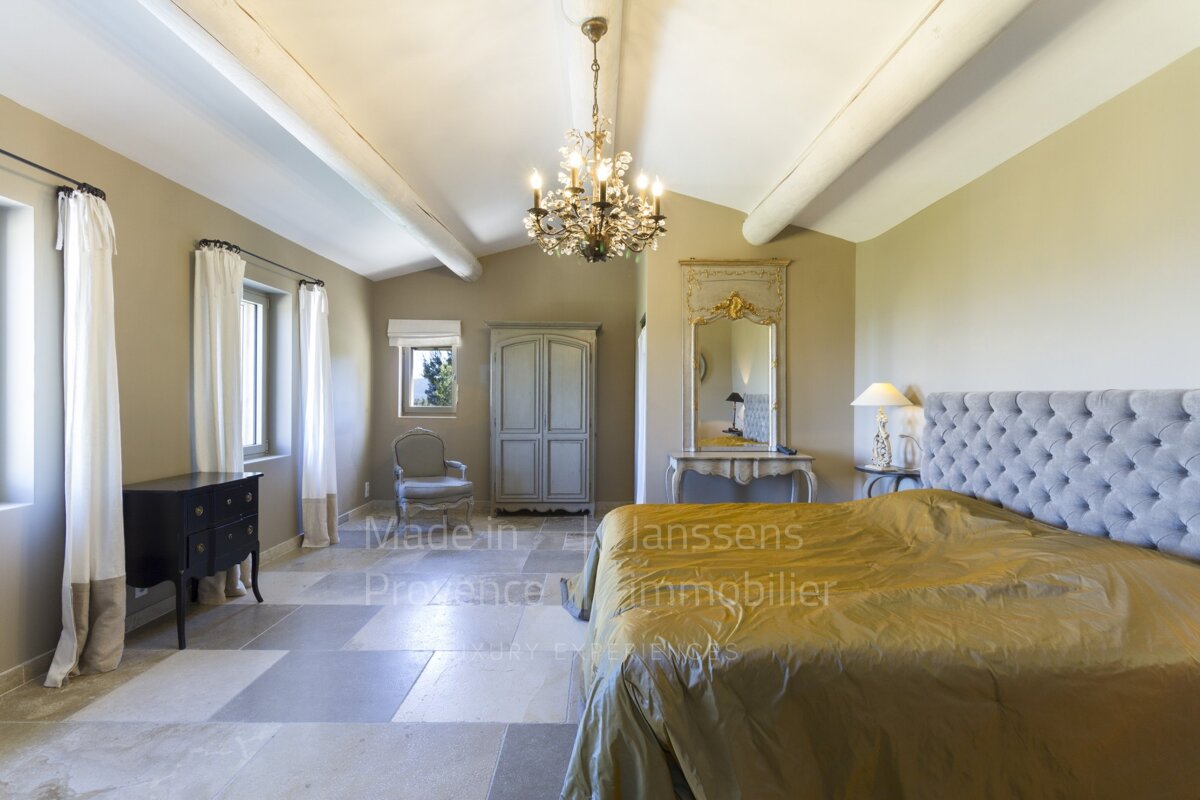 A bedroom with two beds and a chandelier made by janssens provence immobilier
