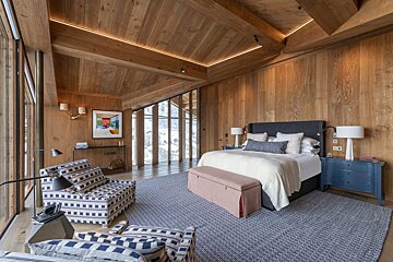 A bedroom with a large bed and a chair