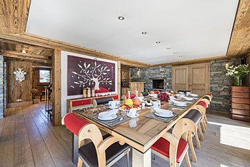 A dining room with a large table and chairs