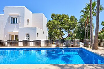 A large white house with a wooden fence around the pool