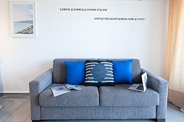 A gray couch with blue pillows and a laptop on it