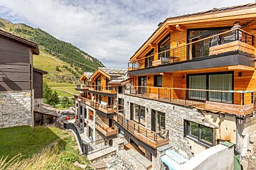 A row of buildings with balconies and mountains in the background