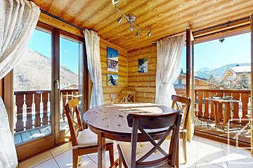 A dining room with a table and chairs and a balcony