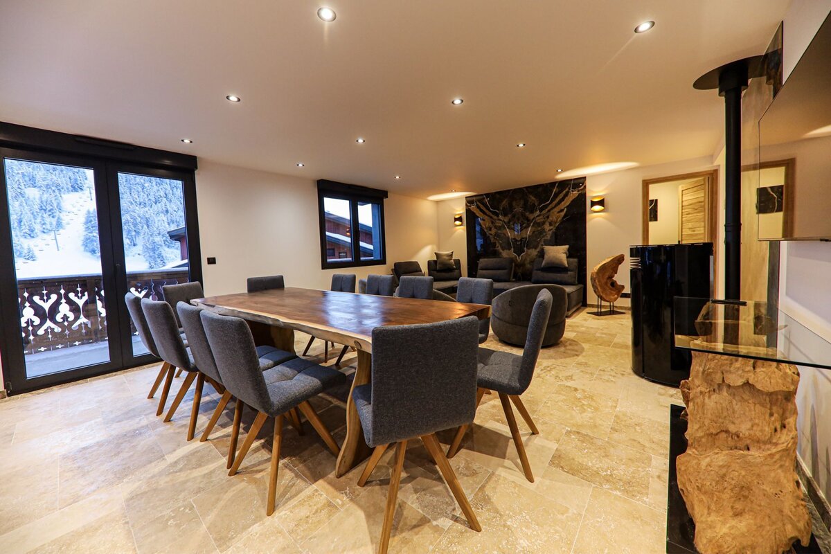 A dining room with a large wooden table and chairs