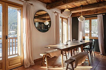 A dining room with a table and chairs and a mirror