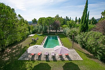 A large swimming pool surrounded by chairs and umbrellas
