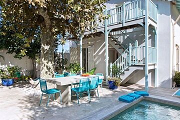 A patio with a table and chairs next to a pool