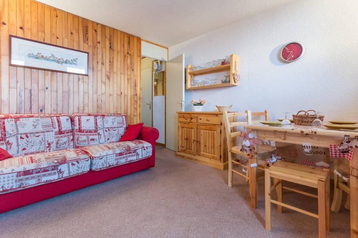 A living room with a couch and a table with a clock on the wall