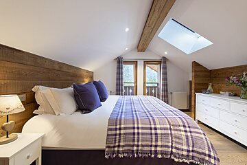 A bedroom with a purple plaid blanket on the bed