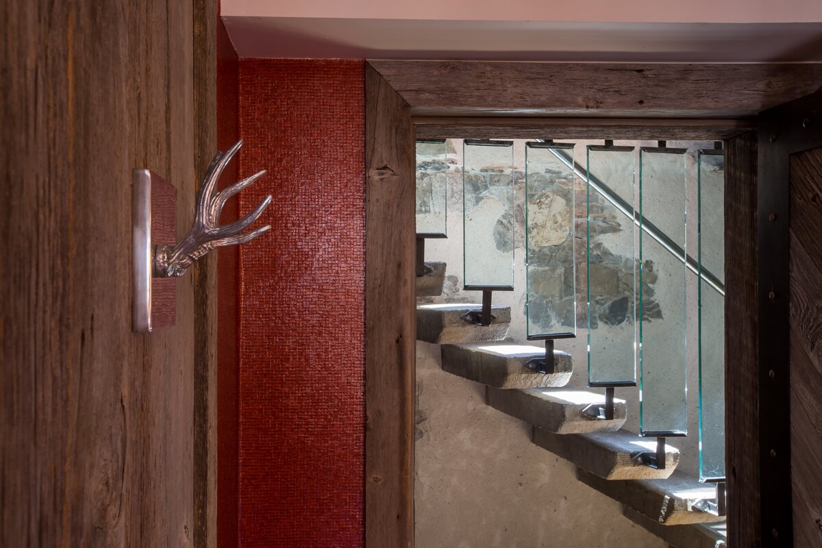 A deer head hangs on a wooden wall next to a staircase