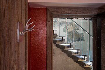 A deer head hangs on a wooden wall next to a staircase