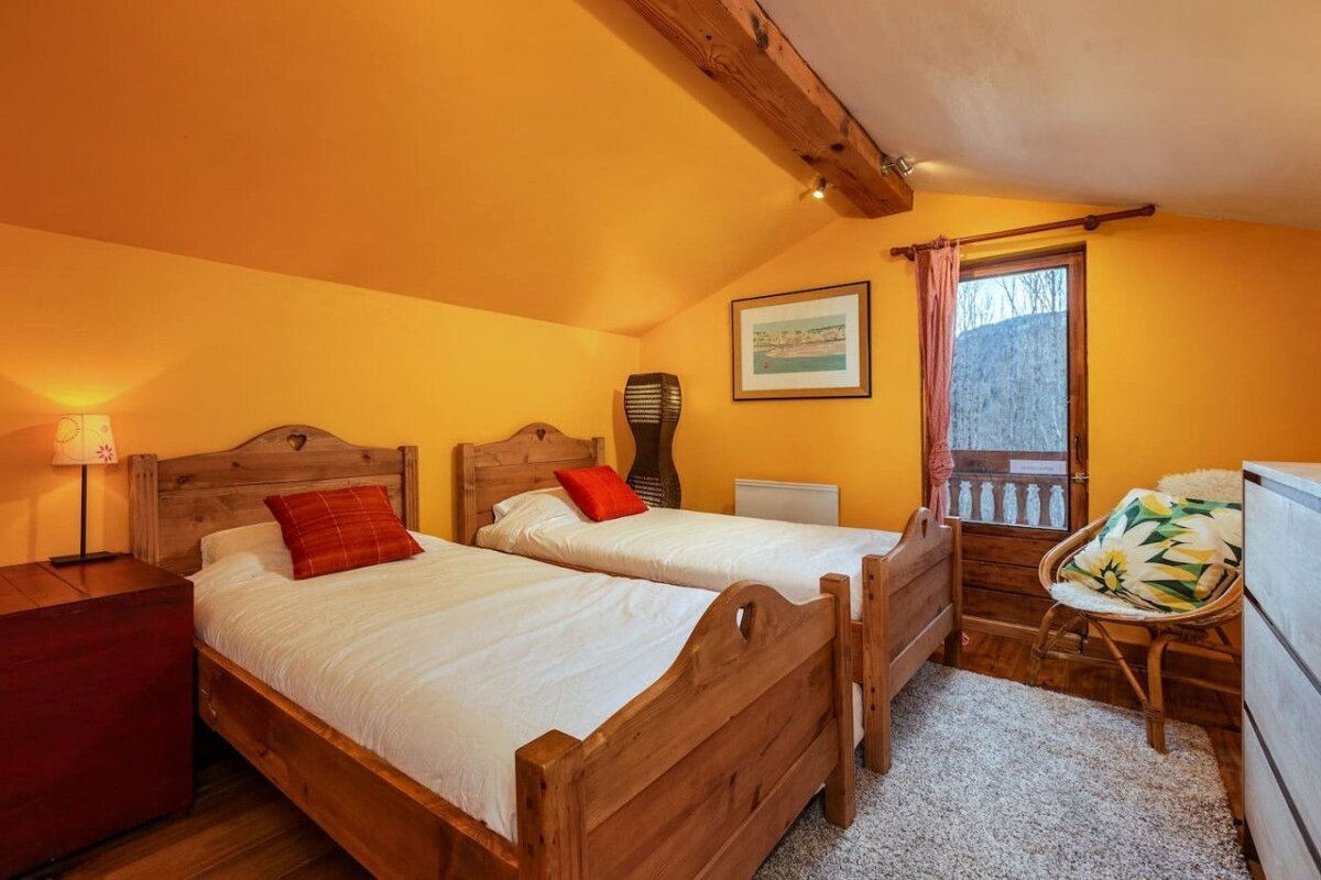 A bedroom with two twin beds and a chair