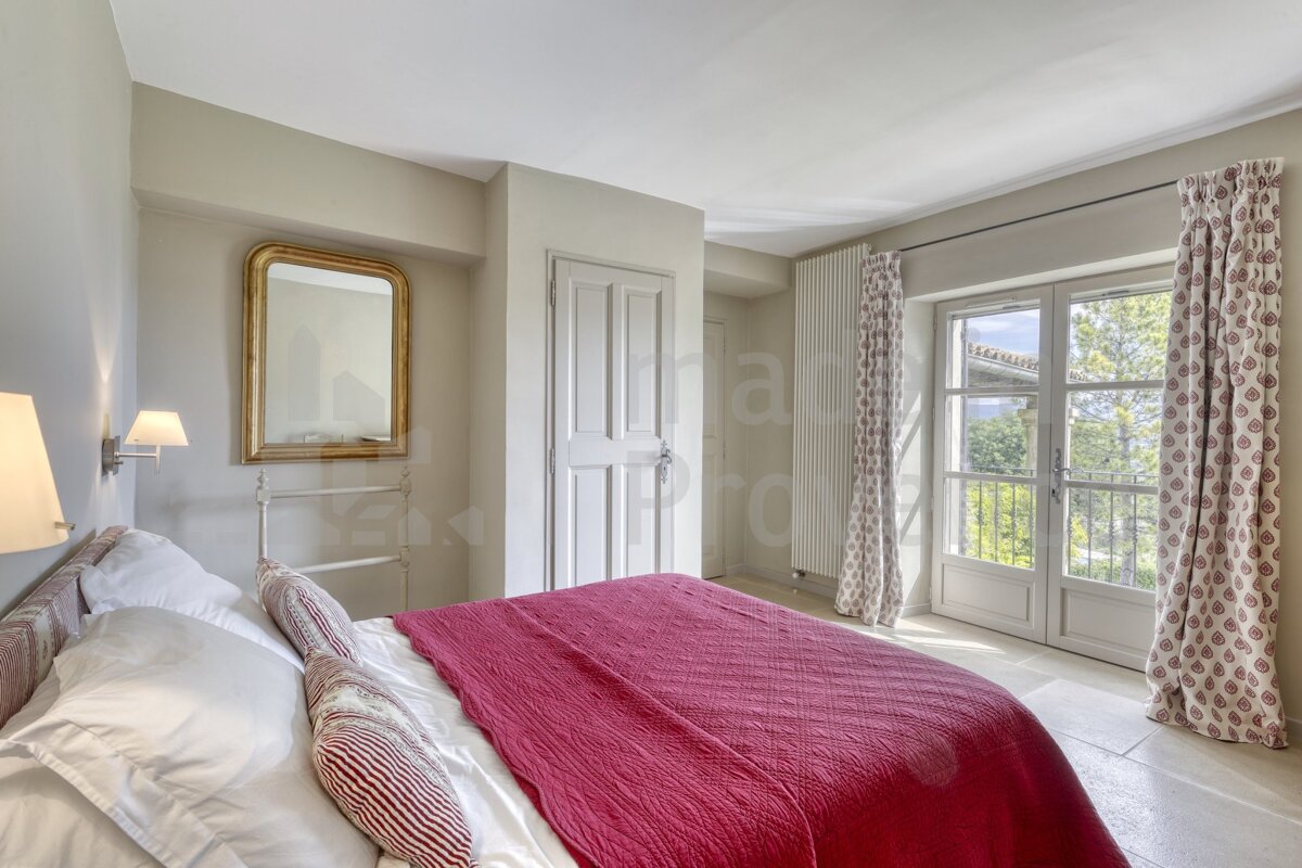 A bedroom with a red blanket and a mirror