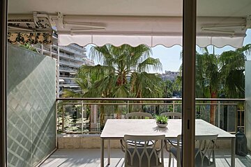 A table and chairs on a balcony with palm trees in the background
