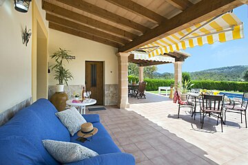 A patio with a blue couch and a yellow and white awning