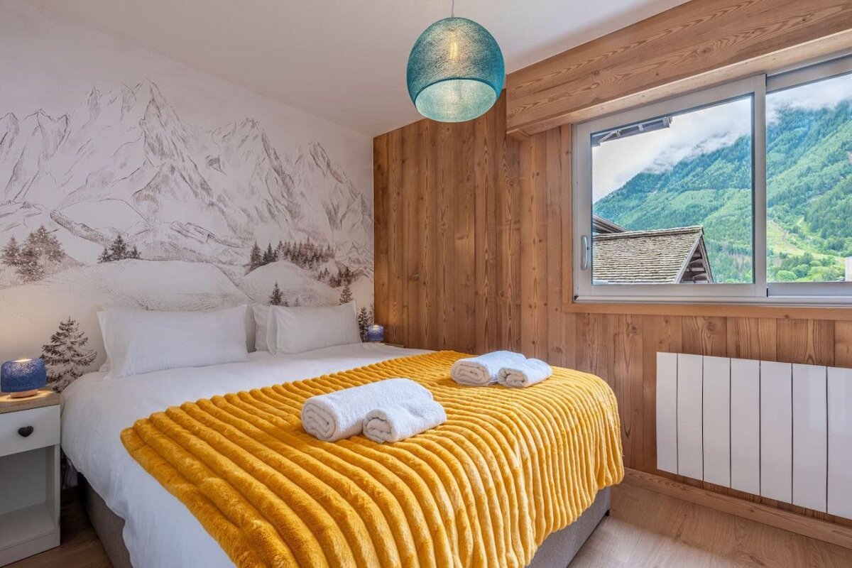 A bedroom with a painting of mountains on the wall