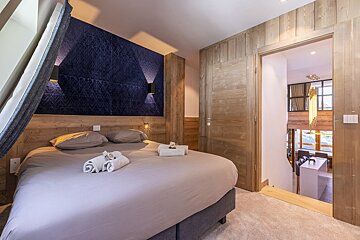 A bedroom with a large bed and a blue wall