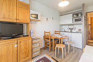 A small kitchen with a table and chairs and a flat screen tv