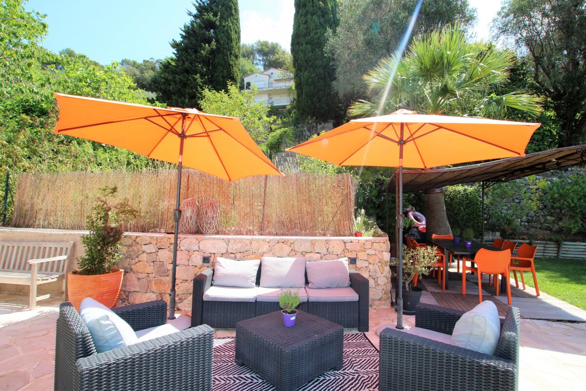 A patio with a couch and chairs under orange umbrellas