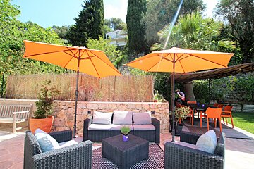 A patio with a couch and chairs under orange umbrellas