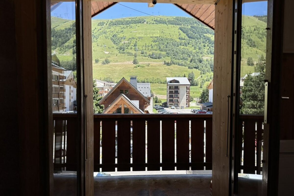 A view of a mountain from a balcony with a wooden railing