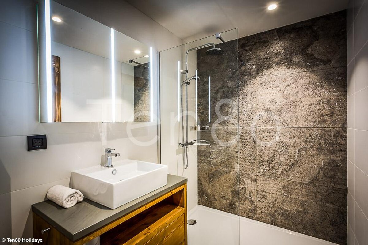 A bathroom with a sink and a shower with the words ten80 holidays on the wall