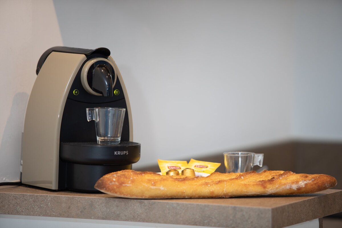 A krups coffee maker sits on a counter next to a loaf of bread