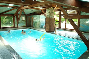People are swimming in an indoor pool with a sign on the wall that says