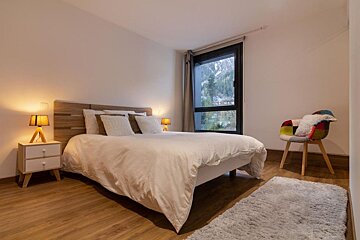 A bedroom with a bed a nightstand and a chair